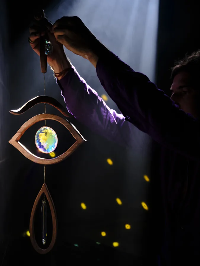 A wooden eye with its crystal lit in a dark room, the spectrum scattered as points of light behind it