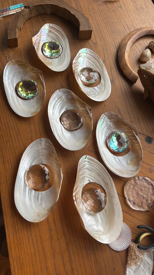 Shell studies seen from above: mother-of-pearl shells on wood, each cradling a faceted crystal